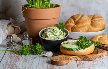 Spicy herb butter, fresh rolls and chopped herb ingredients on cutting board
