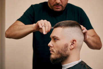 Fototapeta premium hairdresser does hairstyle with scissors in barber shop