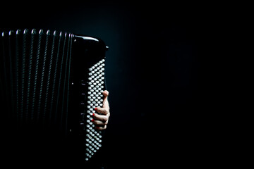 Photographie d'une main jouant d'un accordéon chromatique noir.