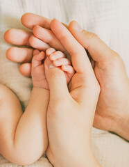 Close-up hands of father, mother and their newborn baby. Hand in hand