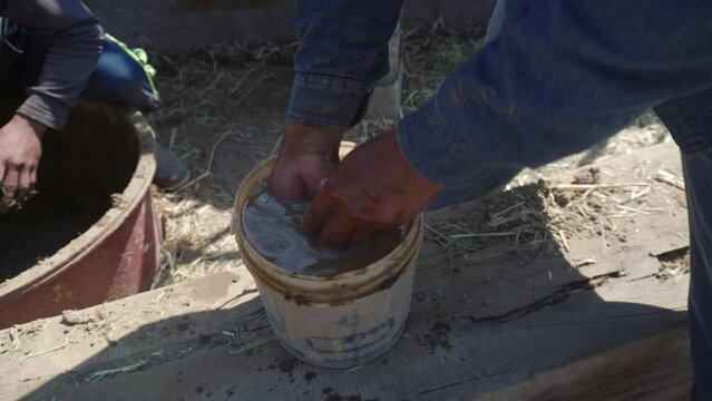 hands a man building a wall with reed and mud