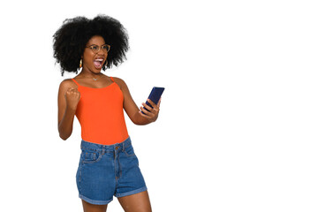 positively surprised young woman celebrates, holds a smart phone in one hand, black power afro...