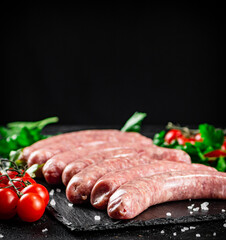 Raw sausages on a stone board with spices, tomatoes and herbs. 