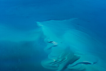 Aerial view of turquoise water surface and a small atoll in Bahamas, Caribbean Sea in Atlantic Ocean. 