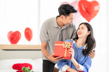 Asian couple Showing love surprise giving flowers or gifts to each other on important occasions such as Valentine's Day birthdays or wedding anniversaries with love and warmth in bedroom of their home