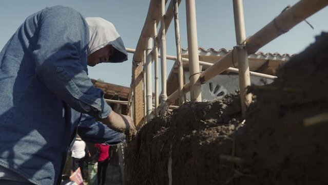 man building a wall with reed and mud, bioconstruction