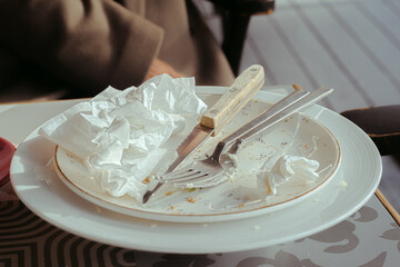 Empty dirty white plate with fork and spoon