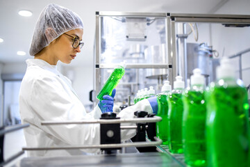 Female technologist controlling production of cleaning supplies or sanitation chemicals for...