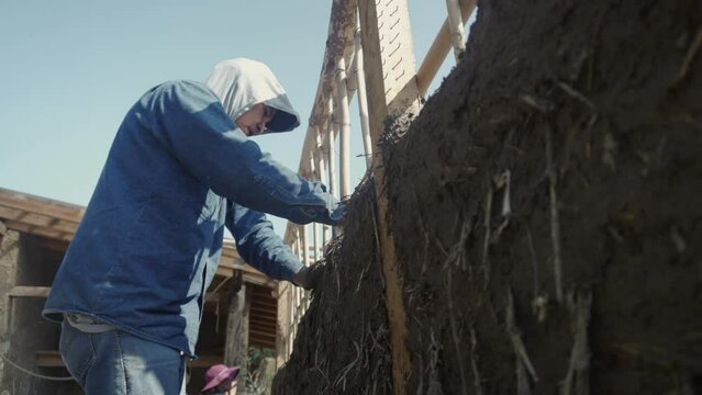 man building a wall with bioconstruction techniques
