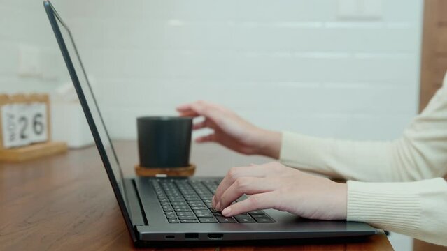 Close-up woman hand is typing laptop keyboard in home office