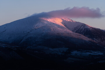 Blencathra catches the first light at sunrise during winter.  Snow-capped mountain in the Lake District, Cumbria, North england, UK. 
