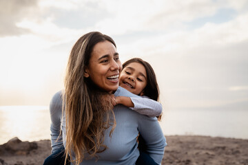 Happy Latin mother enjoying time with her child on the beach - Family and love concept - 563341596