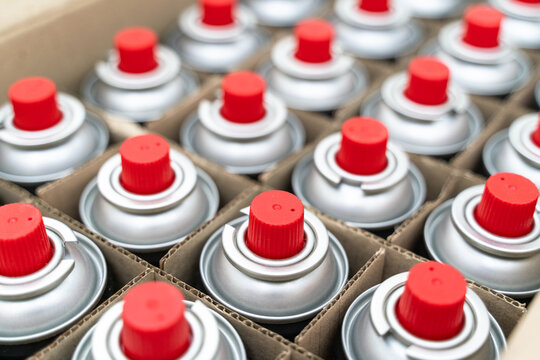 Spray cans packed in cardboard box. Portable liquefied gas bottles