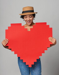 Mixed race african american caucasian girl in straw hat holding big paper pixel style heart shape...