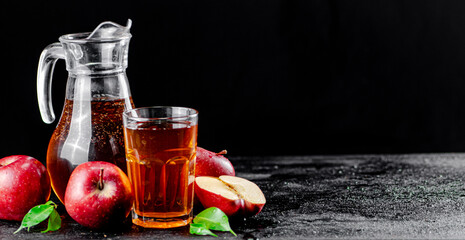 Apple juice in a jug and a glass on the table. 