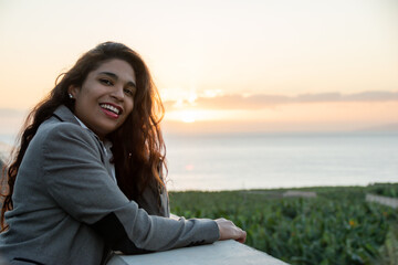 Smiling businesswoman enjoying the sunset from her office balcony. Copy space on the right.