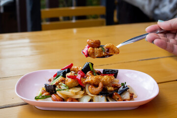 Thai-style stir-fried chicken with cashew Nuts, popular Thai food, served in plate on wooden table.