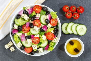 Greek salad with fresh tomatoes olives and feta cheese healthy eating food from above on a slate