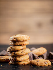 Pile of homemade cookies with pieces of milk chocolate on the table.