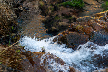 Agua de un arroyo deslizándose entre rocas.