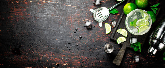 Margarita on a cutting board with pieces of lime and mint leaves. 