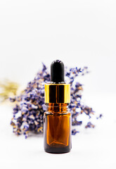 one bottle of essential lavender oil and bunch of lavender flowers with dry lavender flowers on white background	