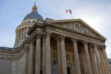 Fototapeta na wymiar Pantheon building in Paris, France with focus on French flag over blue sky.