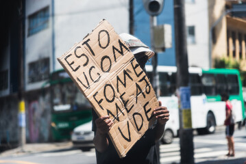 Beggar asking for money and food with a sign in traffic in Salvador, Bahia.