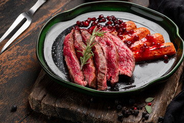 Flank steak fried and chopped with vegetables and cranberry sauce. Beef steak on a plate in rustic style, close up