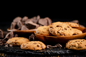 Cookies with pieces of milk chocolate on a stone board.  - obrazy, fototapety, plakaty