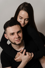 Relationships, feelings and tenderness in the young family of men and girl. Love story of a couple spending time in cozy room at home. Couple in love hugging and kissing on couch at home.