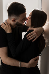 Love story of a couple spending time in cozy room at home. Couple in love hugging and kissing on couch at home. Relationships, feelings and tenderness in the young family of men and girl.