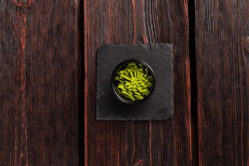 Green wasabi sauce or paste in bowl on wooden background top view