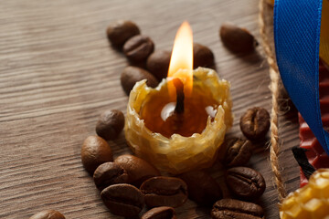 Fototapeta na wymiar a burning natural wax candle, on the background natural wax with honeycombs and a wick