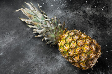 Yellow Pineapple or ananas, on black dark stone table background, with copy space for text