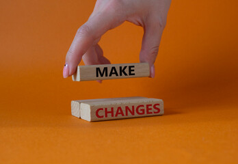 Make changes symbol. Wooden blocks with words Make changes. Businessman hand. Beautiful orange background. Business and Make changes concept. Copy space.