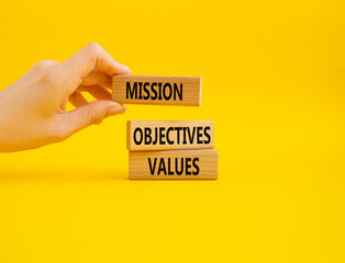 Mission Objectives Values symbol. Concept words Mission Objectives Values on wooden blocks. Beautiful yellow background. Businessman hand. Business and Mission Objectives Values concept. Copy space