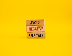 Avoid negative self-talk symbol. Concept words Avoid negative self-talk on wooden blocks. Beautiful yellow background. Business and Avoid negative self-talk concept. Copy space.