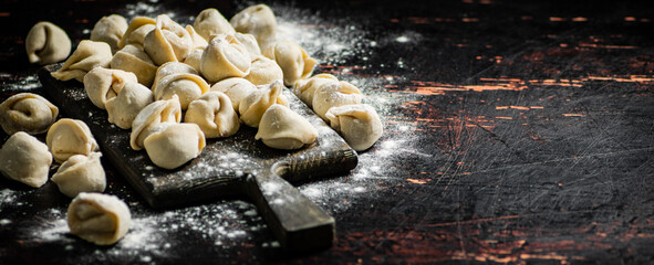 Raw homemade dumplings on a flour cutting board. 