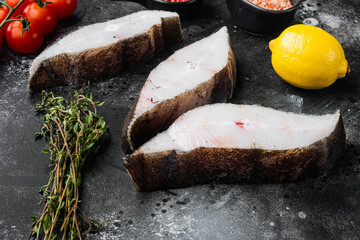 Chilled halibut steaks, with ingredients and rosemary herbs, on black dark stone table background