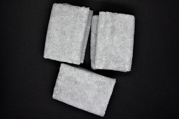 Three gray towels on a black background. Terry cloths for wiping furniture. Towels on a black background. - obrazy, fototapety, plakaty