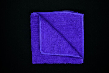 A cloth for wiping. Purple cloth on a black background. Towel.
