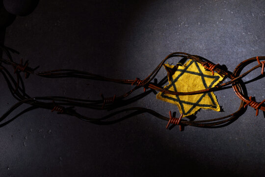 Holocaust memory day. Barbed wire, stones and yellow star on dark background