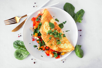 Healthy vegetable loaded omelette. Top down view table scene over a white marble background.