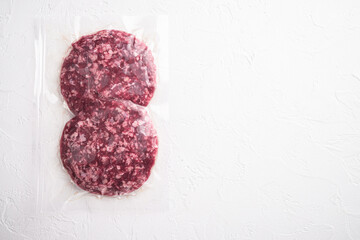 Burger beef veal cutlets in vacuum plastic, on white stone  background, top view flat lay, with...