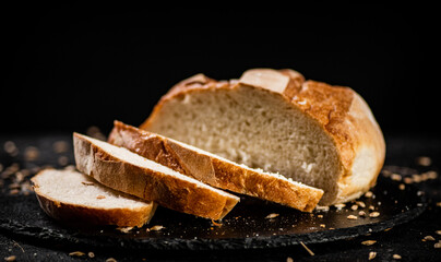 Sliced on a stone board wheat bread with grains. 