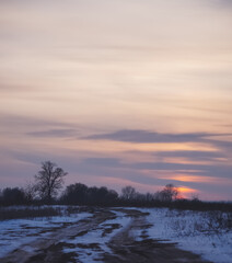 Winter landscape in the evening in the fields of Slobozhanshchina, clouds and the setting sun on the horizon