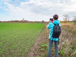 Woman takes photo of field with Cape Arkona lighthouse. Baltic Sea