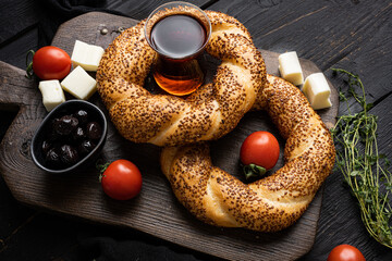 Bagel Simit with sesame traditional pastry with breakfast ingredients olive and tomato cheese, on...