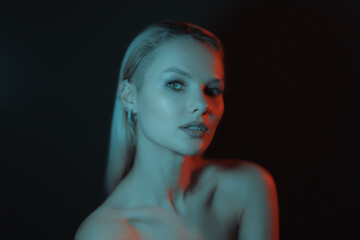 Fototapeta premium Fashion woman portrait on dark background with soft blue and red lights play on skin and copy space.
